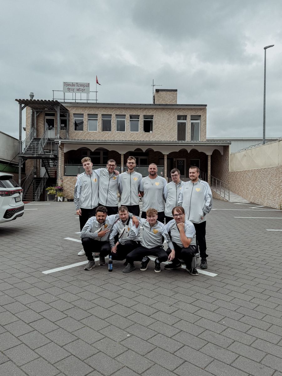 Die Mannschaft in zwei Reihen vor dem Gebäude, alle in den grauen Trainingsjacken