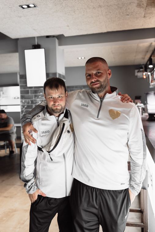 Zwei Spieler stehen nebeneinander, einer legt dem anderen den Arm um die Schulter