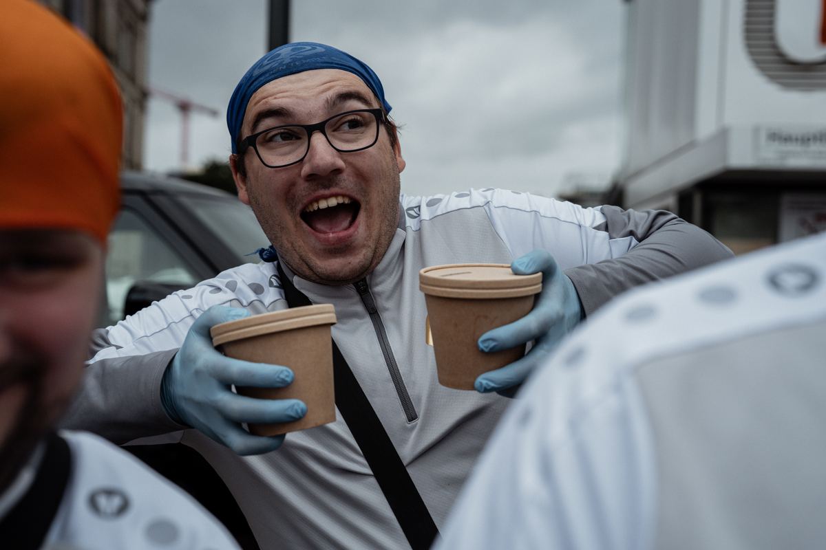 Bei der Essensausgabe reichen mehrere Hände Becher und Schalen weiter