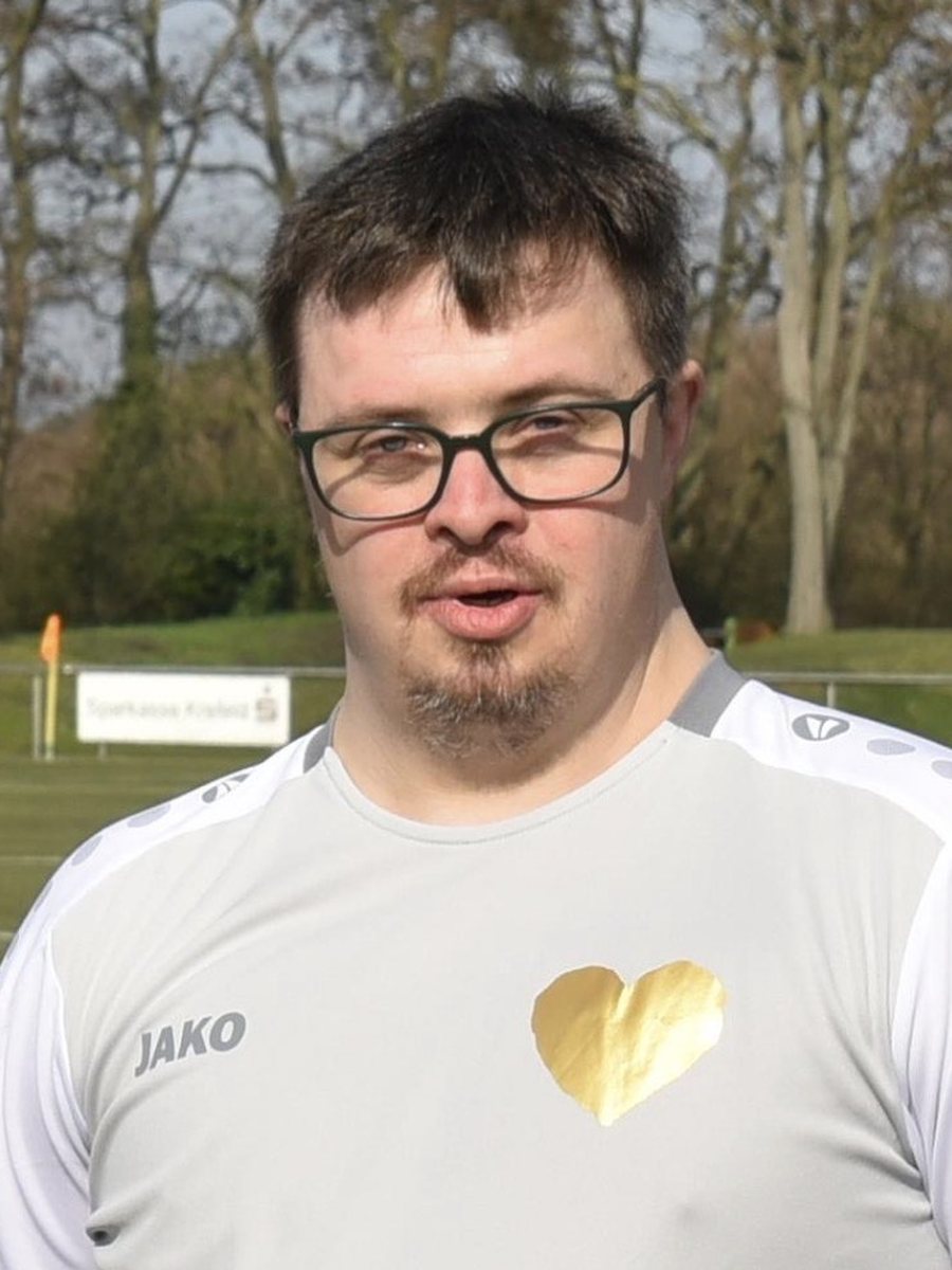 Jonas im weißen Trikot der Inklusionsmannschaft auf dem Sportplatz